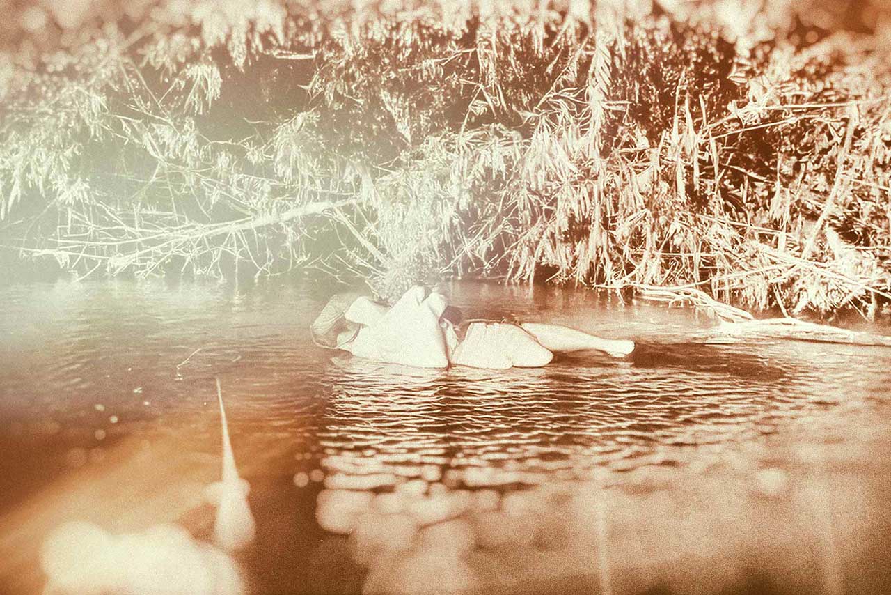 person treibt entspannt im wasser, von licht durchzogen, umgeben von natur
