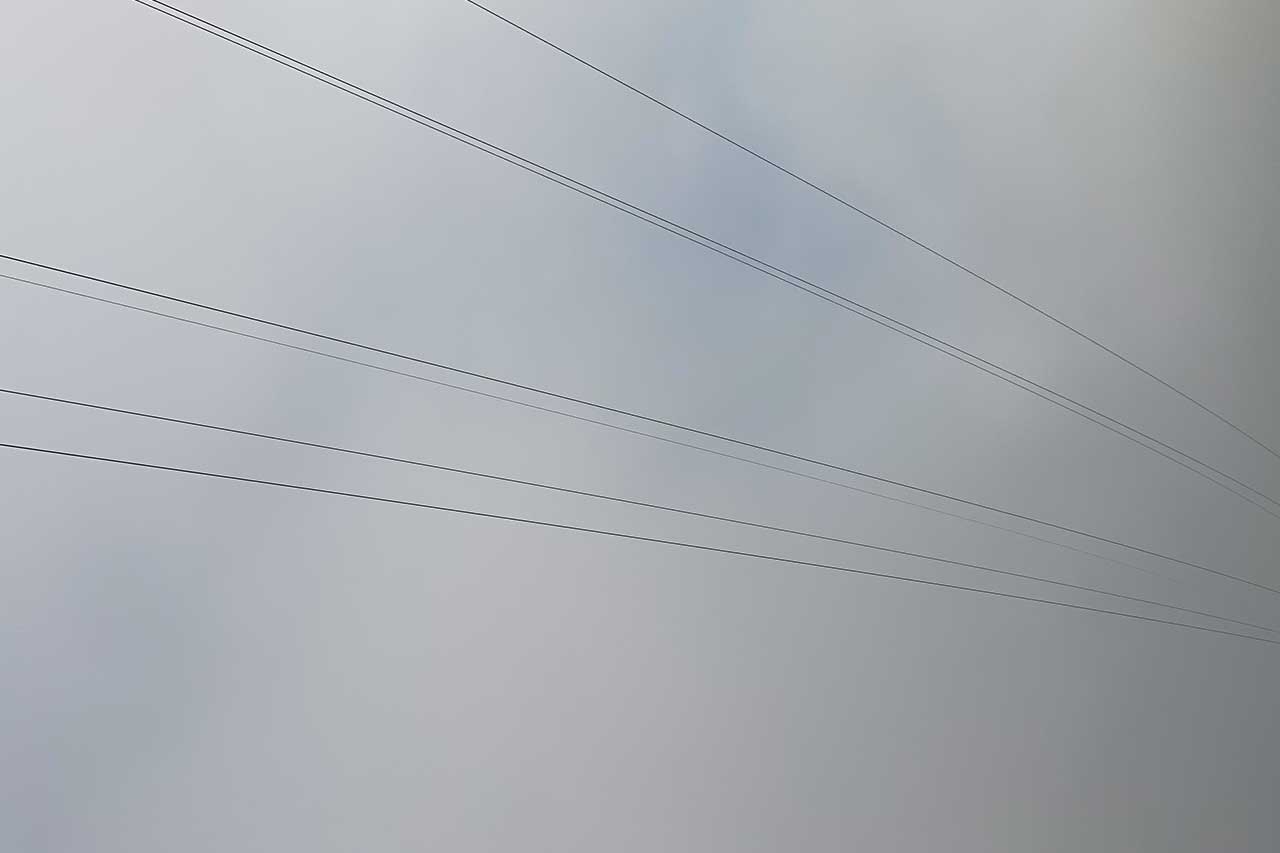 stromleitungen vor grauem himmel, verlaufend in die stille