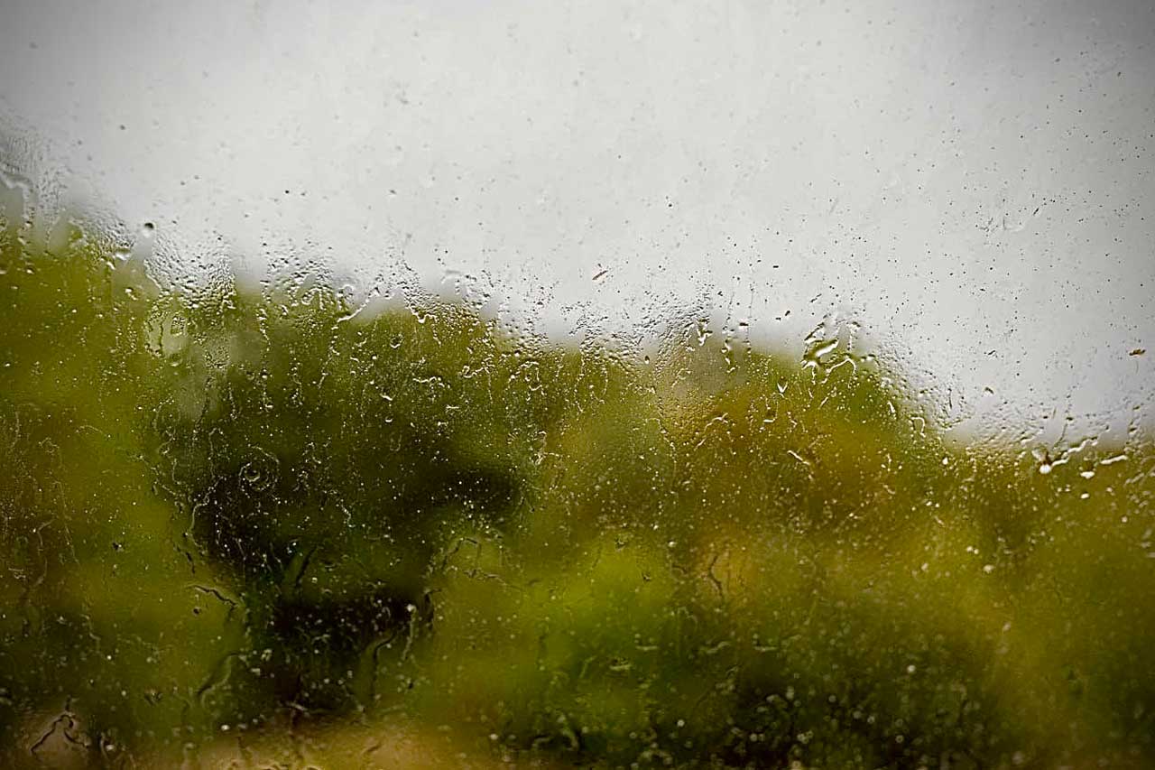 regengetränktes fenster vor verschwommener landschaft – stille und unschärfe im übergang