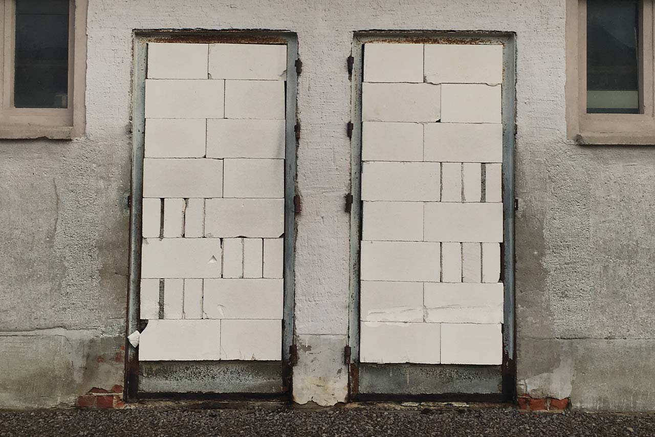 Zwei Türen in einer Mauer, vollständig zugemauert mit weißen Bausteinen, als Symbol für versperrte Wege oder verborgene Möglichkeiten.