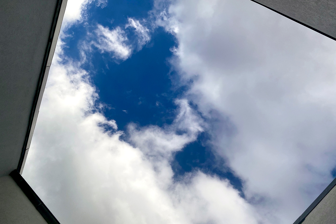 Blick in einen Himmel zwischen Gebäudewänden – wolkenverhangen, offen
