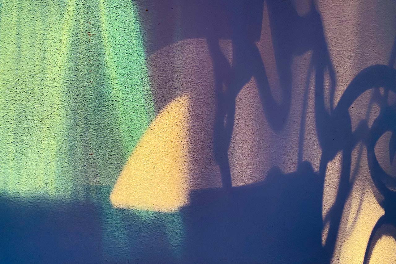 Farbige Schatten und Lichtreflexe auf rauer Wandoberfläche – abstrakt, poetisch, atmosphärisch.