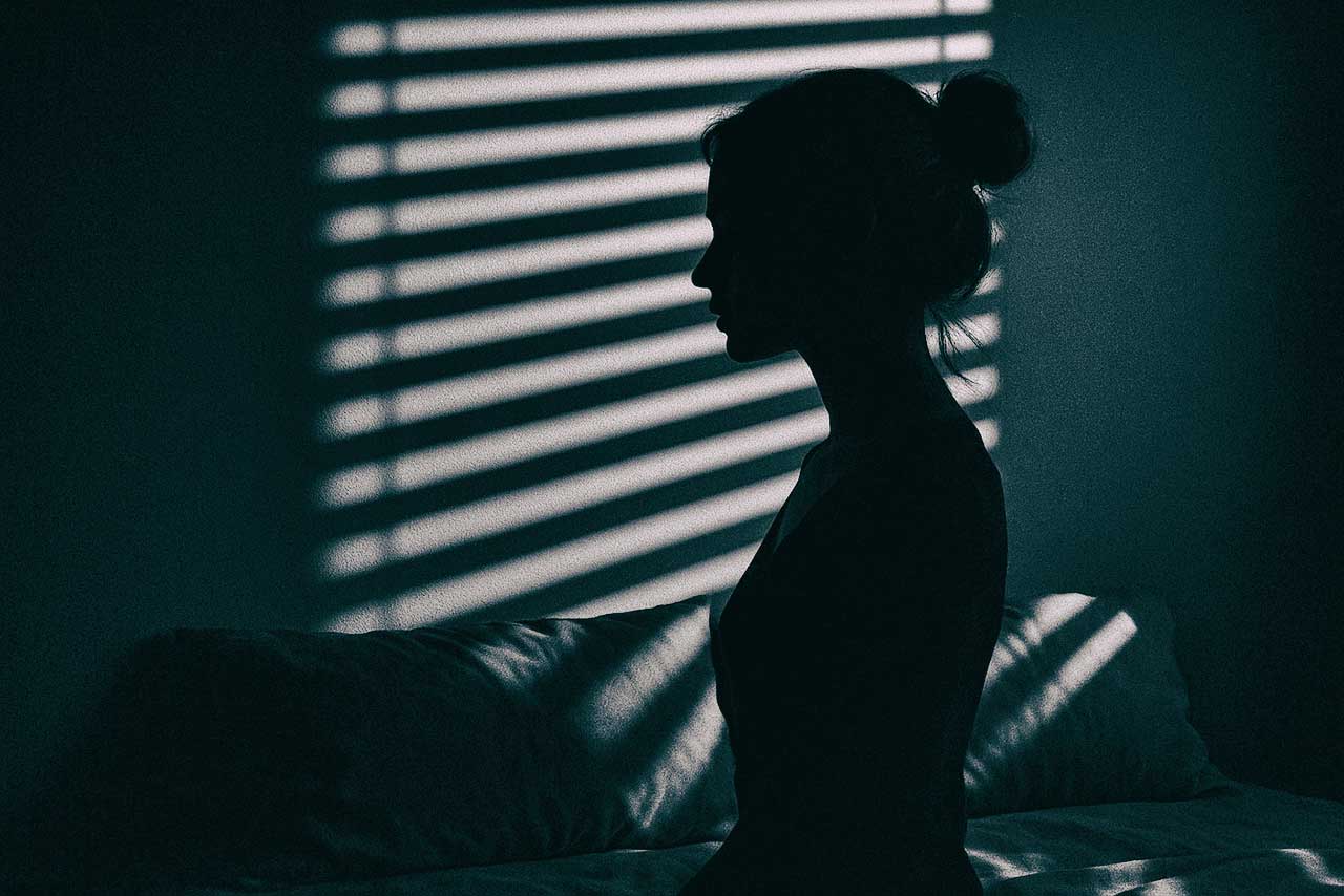 schattenriss einer frau vor jalousienlicht auf einem bett, stille szene