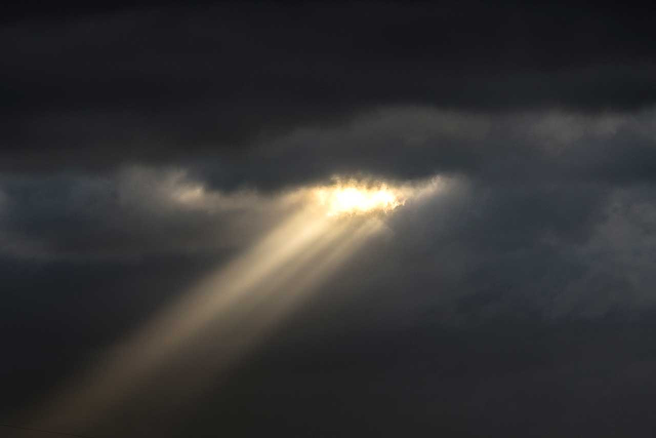 ein schmaler lichtstrahl fällt durch dunkle wolken